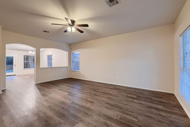 spare room with arched walkways, dark wood finished floors, visible vents, and a ceiling fan