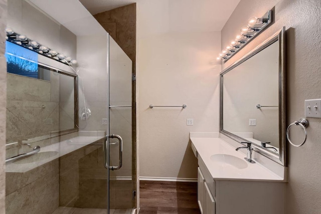 full bath with a stall shower, baseboards, wood finished floors, and vanity