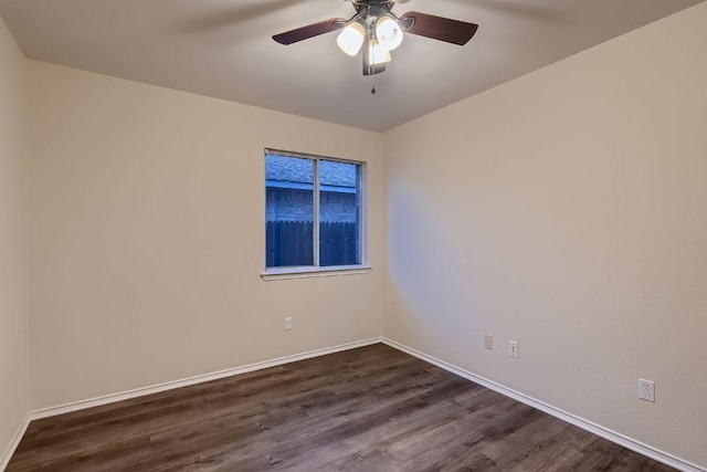 spare room with a ceiling fan, baseboards, and dark wood-type flooring