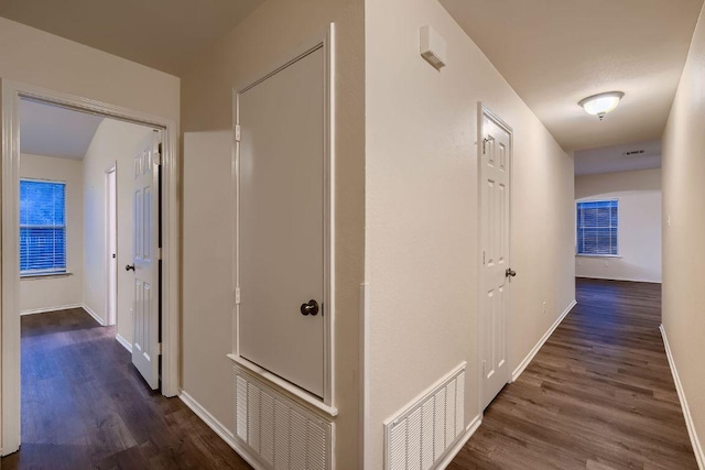 hallway featuring wood finished floors, visible vents, and baseboards