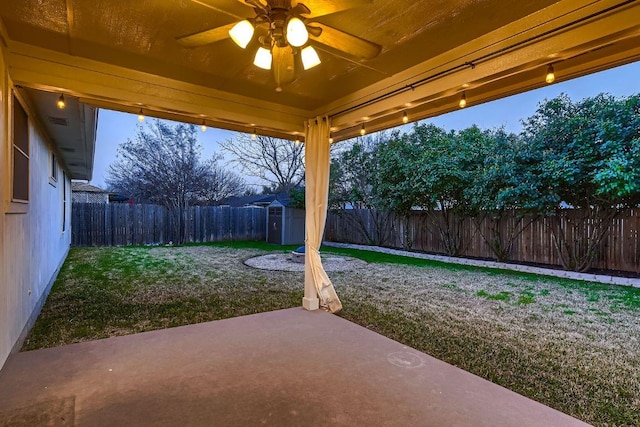 view of patio with a storage shed, a fenced backyard, ceiling fan, and an outbuilding