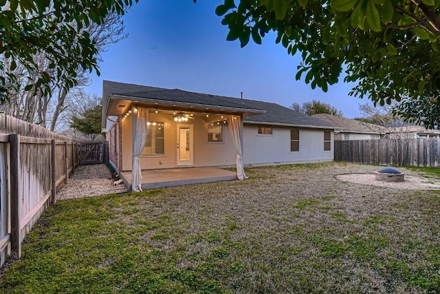 back of house with stucco siding, a fenced backyard, a ceiling fan, and a patio