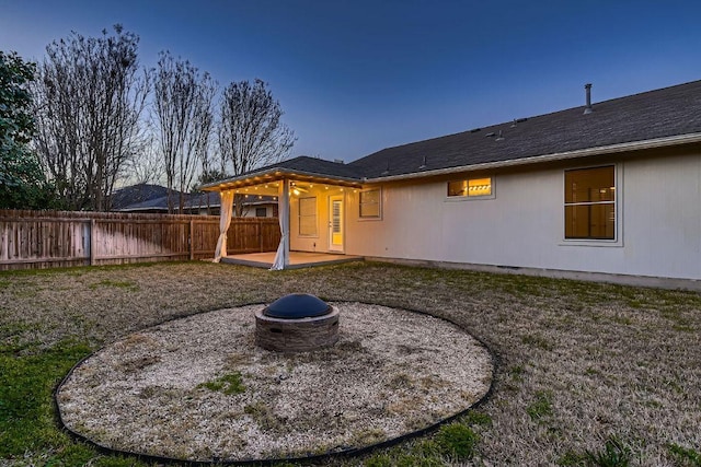 rear view of property with fence, a fire pit, and a patio