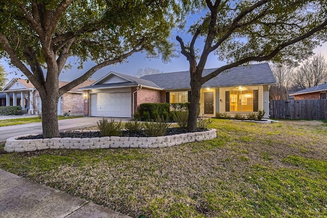 ranch-style home featuring concrete driveway, an attached garage, fence, a front lawn, and brick siding