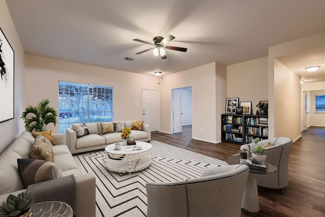 living room with baseboards, ceiling fan, visible vents, and dark wood-style flooring