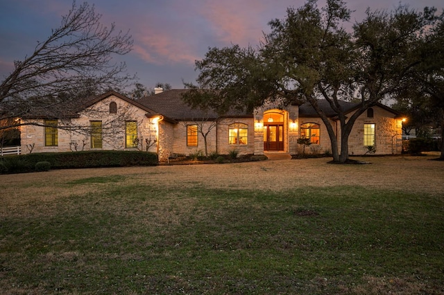 view of front of property with a front yard, stone siding, and a chimney