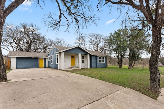 view of front of property with an outbuilding, concrete driveway, brick siding, and a front yard