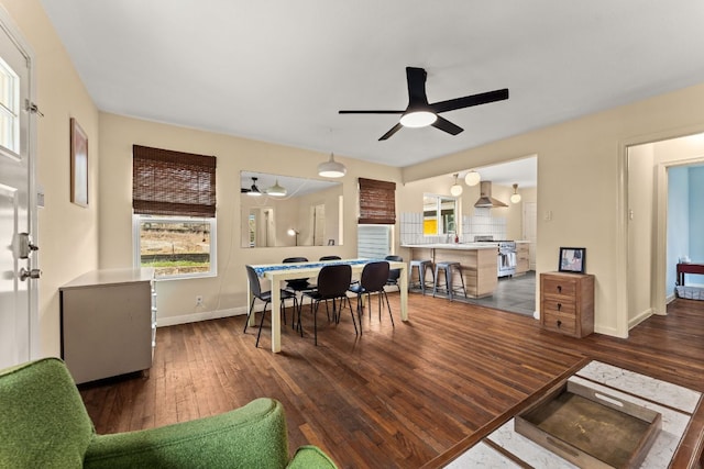 dining area with dark wood finished floors, a ceiling fan, and baseboards