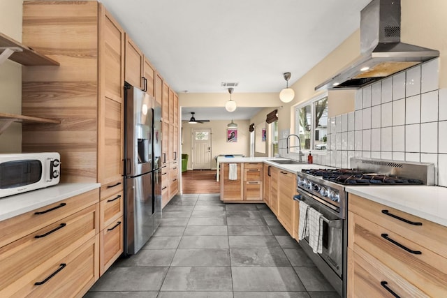 kitchen with appliances with stainless steel finishes, a sink, range hood, light brown cabinetry, and backsplash