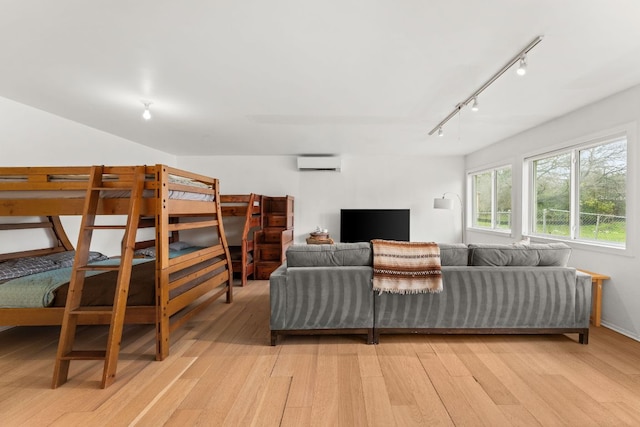 bedroom with light wood-style floors and a wall mounted air conditioner