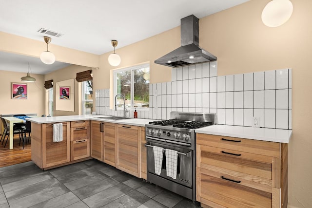 kitchen featuring backsplash, a sink, ventilation hood, high end stove, and a peninsula