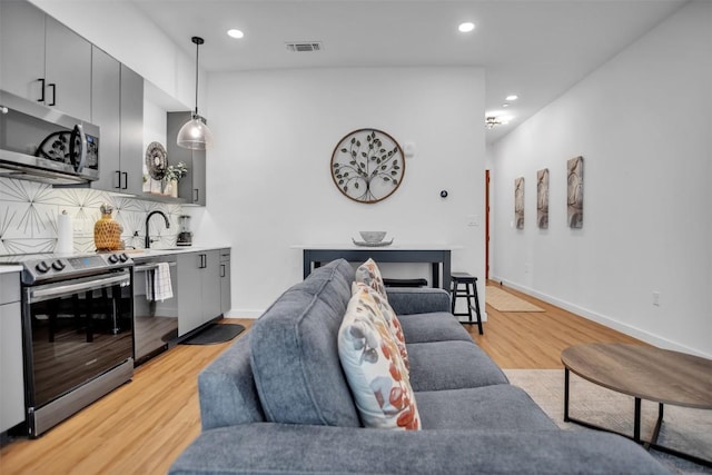 living room with recessed lighting, visible vents, baseboards, light wood-style floors, and wet bar