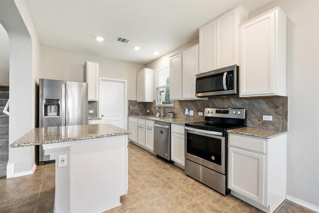 kitchen featuring tasteful backsplash, visible vents, arched walkways, stainless steel appliances, and a sink