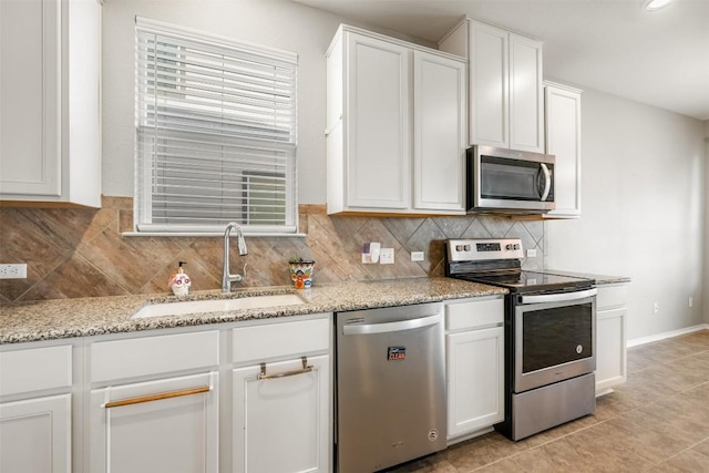 kitchen with decorative backsplash, light stone counters, appliances with stainless steel finishes, white cabinetry, and a sink