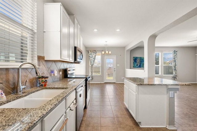 kitchen featuring tile patterned flooring, stainless steel appliances, a sink, white cabinetry, and backsplash