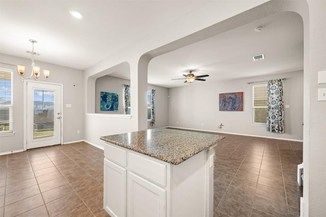 kitchen featuring ceiling fan with notable chandelier, a kitchen island, white cabinetry, open floor plan, and tile patterned floors