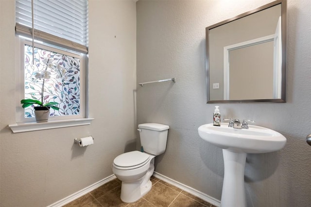 half bathroom featuring toilet, tile patterned flooring, and baseboards