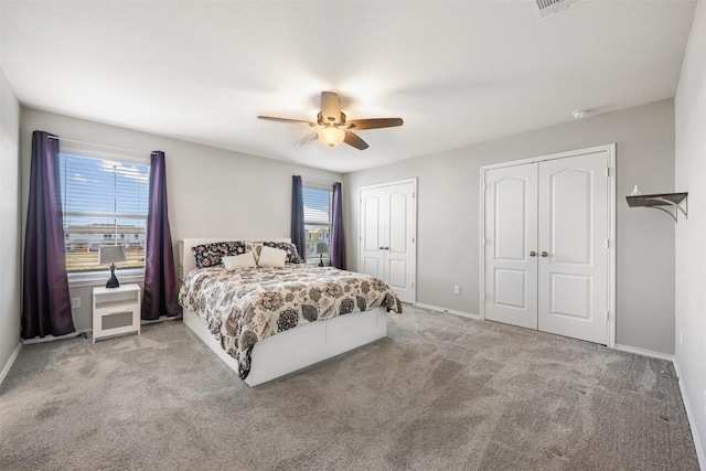 carpeted bedroom featuring baseboards, ceiling fan, and multiple closets