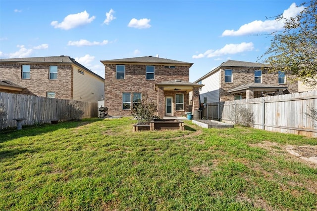 back of house with a yard, brick siding, a fenced backyard, and a vegetable garden