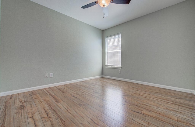 spare room with a ceiling fan, a textured wall, baseboards, and wood finished floors