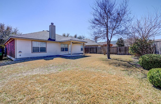 back of property featuring a yard, fence, a chimney, and a patio