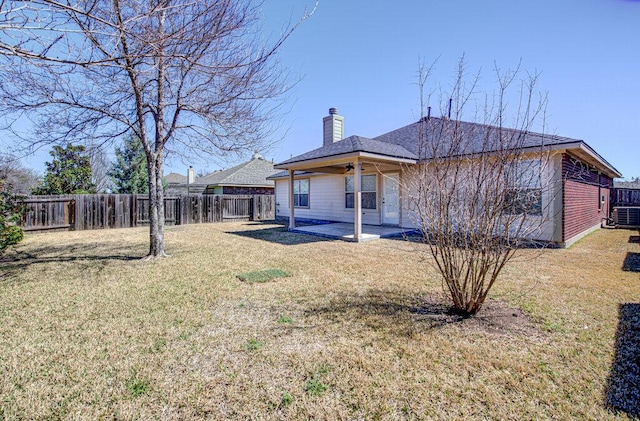 rear view of property with a fenced backyard, a chimney, and a lawn