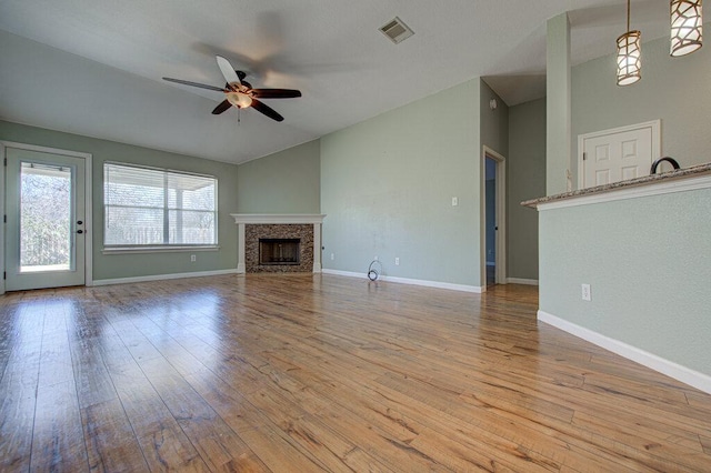 unfurnished living room with visible vents, a ceiling fan, lofted ceiling, hardwood / wood-style flooring, and a fireplace