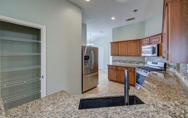 kitchen with light stone counters, visible vents, decorative backsplash, appliances with stainless steel finishes, and a sink