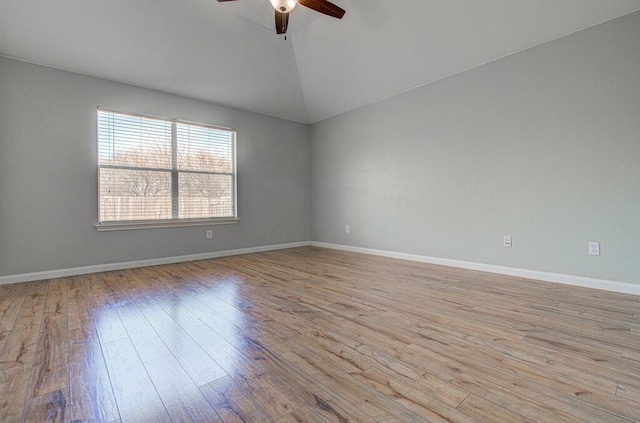 empty room with lofted ceiling, light wood-style floors, baseboards, and a ceiling fan