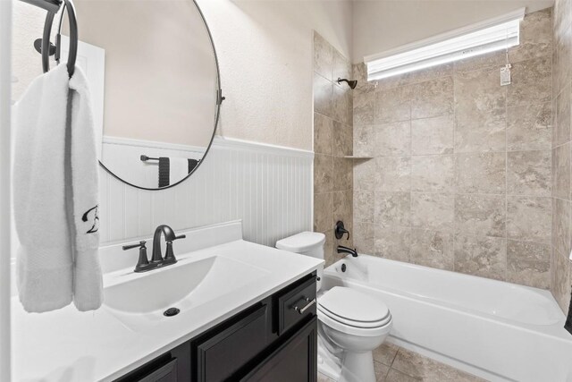 full bathroom featuring bathing tub / shower combination, toilet, wainscoting, tile patterned floors, and vanity