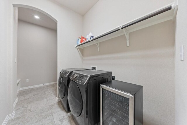 laundry room featuring arched walkways, laundry area, washer and clothes dryer, and baseboards