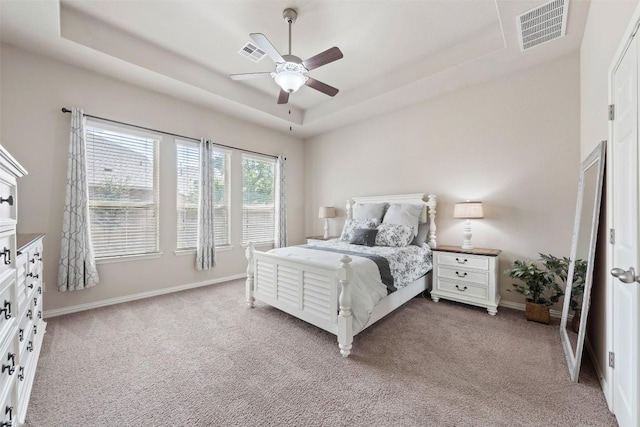 bedroom featuring carpet flooring, a raised ceiling, visible vents, and baseboards