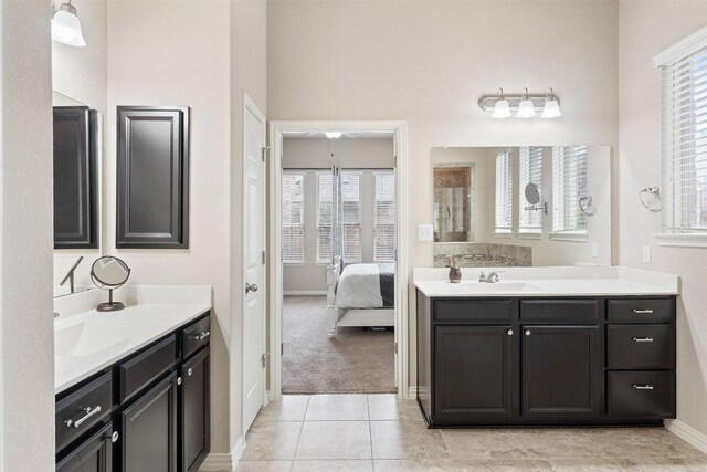 ensuite bathroom with ensuite bathroom, two vanities, a sink, and tile patterned floors