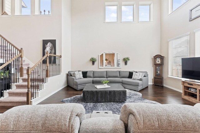 living room featuring baseboards, a high ceiling, stairway, and dark wood-type flooring