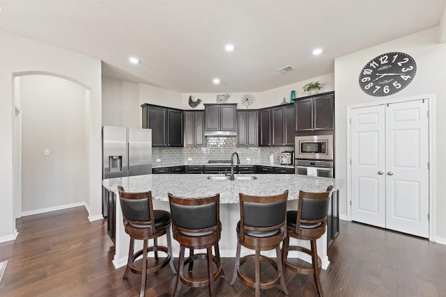 kitchen with tasteful backsplash, visible vents, appliances with stainless steel finishes, a kitchen island with sink, and a sink