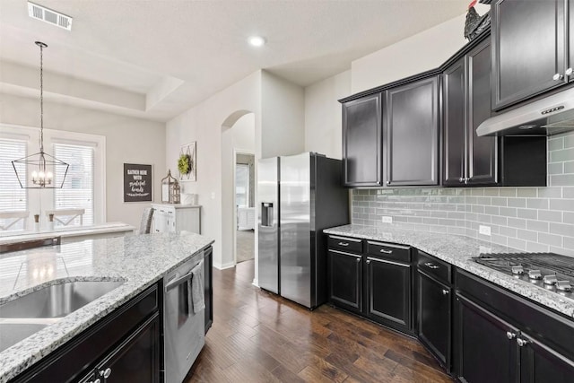 kitchen with stainless steel appliances, visible vents, decorative backsplash, dark cabinetry, and under cabinet range hood