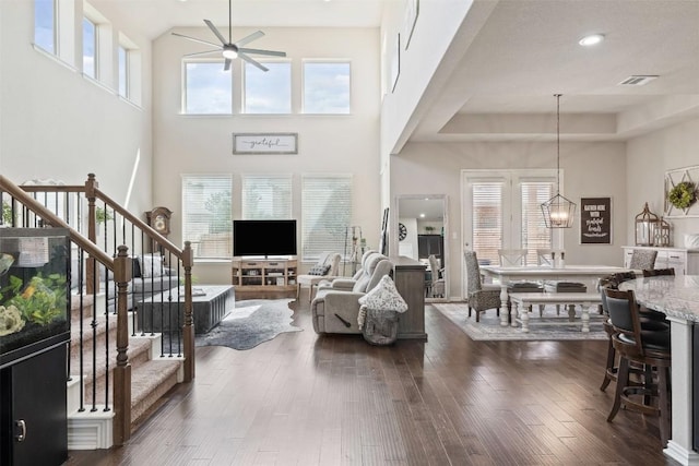 living area featuring stairs, ceiling fan, dark wood finished floors, and visible vents