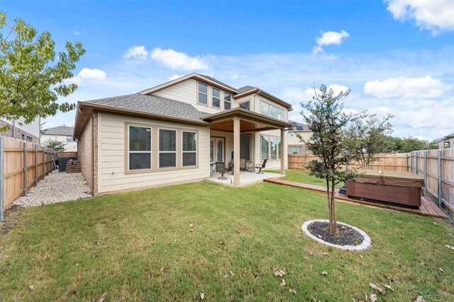 rear view of property featuring a patio, a yard, a fenced backyard, and a hot tub