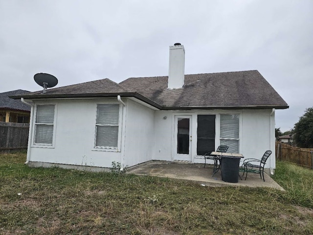 rear view of house featuring a patio, a lawn, a chimney, and fence