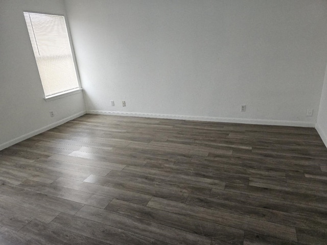 empty room with baseboards and dark wood-type flooring