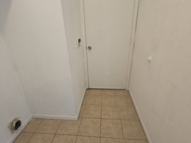 hall featuring baseboards and light tile patterned floors