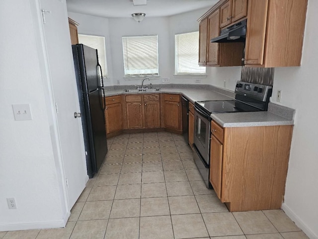 kitchen with light tile patterned floors, under cabinet range hood, a sink, brown cabinets, and black appliances