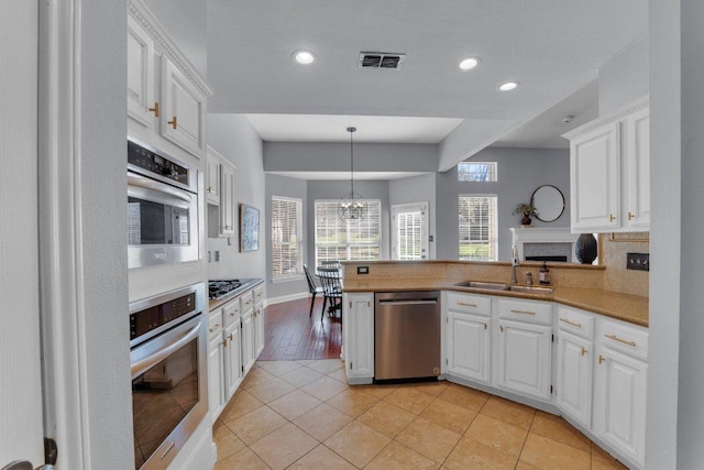 kitchen featuring dishwasher, a sink, visible vents, and white cabinetry