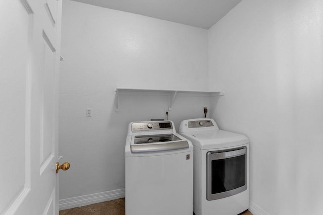 washroom featuring washing machine and dryer, laundry area, and baseboards