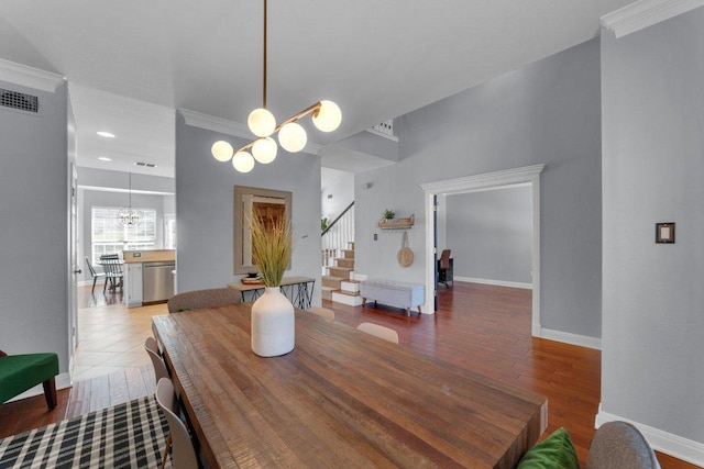 dining area with visible vents, an inviting chandelier, wood finished floors, baseboards, and stairs