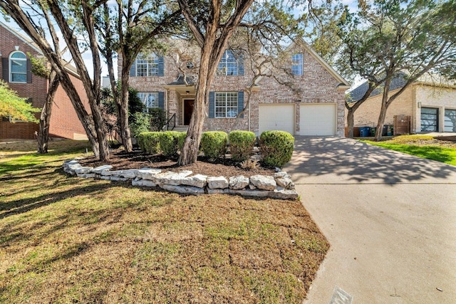 traditional home featuring a garage, a front yard, brick siding, and driveway