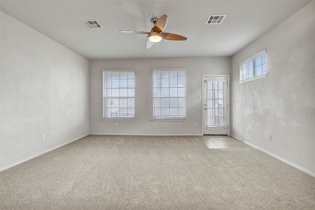 empty room featuring baseboards, a ceiling fan, visible vents, and light colored carpet