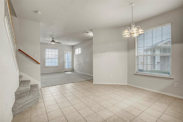 foyer entrance with ceiling fan with notable chandelier, stairway, light tile patterned flooring, and baseboards