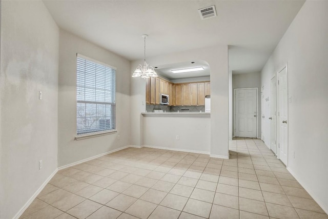 kitchen featuring light tile patterned floors, visible vents, light countertops, stainless steel microwave, and an inviting chandelier