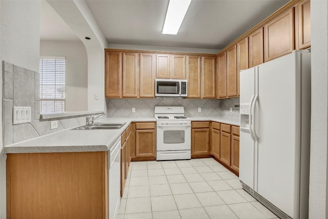 kitchen featuring light tile patterned floors, white appliances, a sink, light countertops, and tasteful backsplash